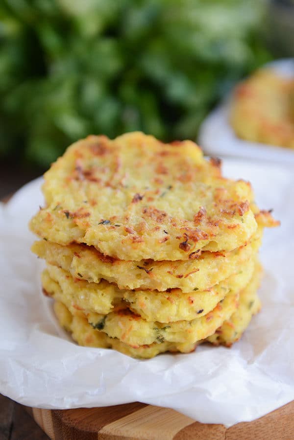 A stack of golden brown spaghetti squash fritters on a piece of parchment.