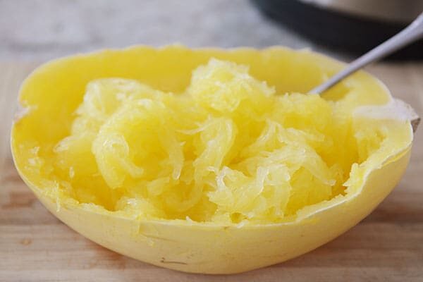 A fork scooping out the insides of a cooked spaghetti squash. 