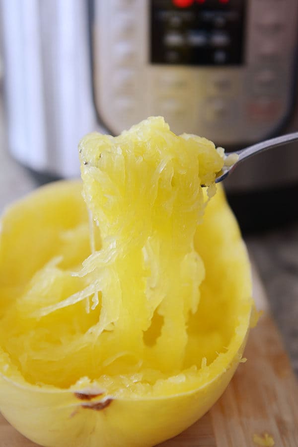 A fork taking cooked strands of spaghetti squash out of the inside of the squash.