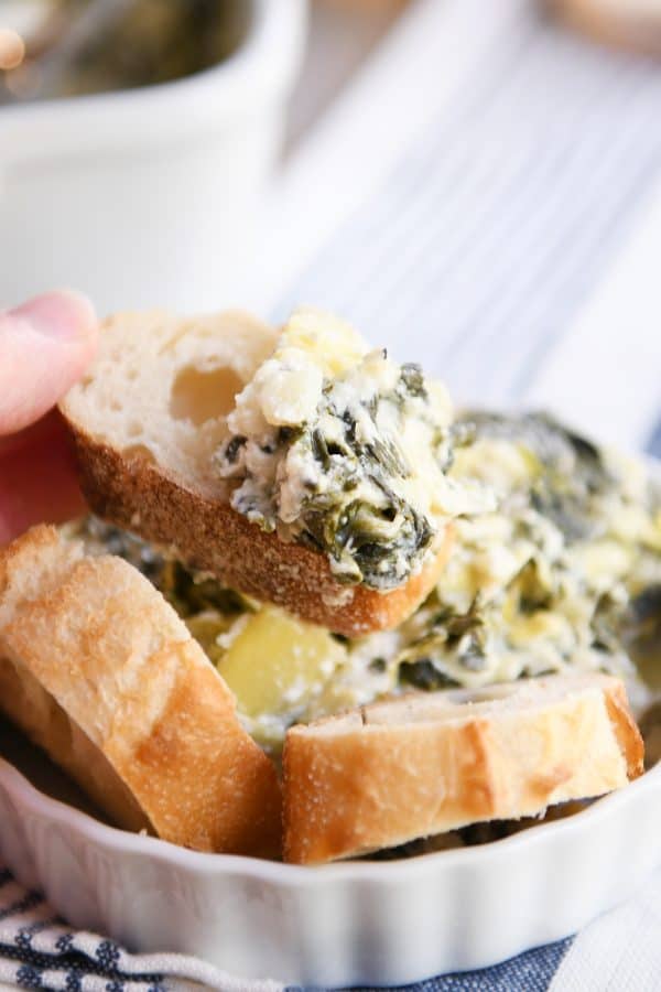 The best spinach artichoke dip in white dish with bread.