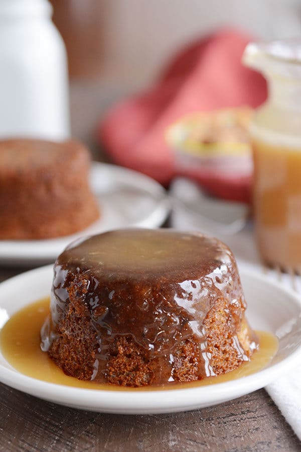 A small, brown cake covered in a light brown sticky toffee sauce.