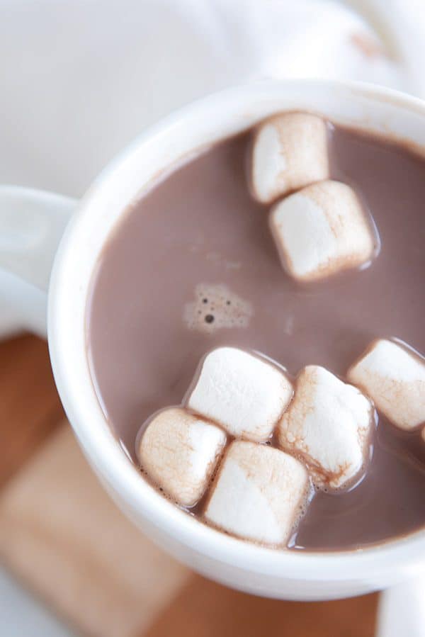 A top-view of a white mug of steaming hot chocolate and marshmallows floating on the top.