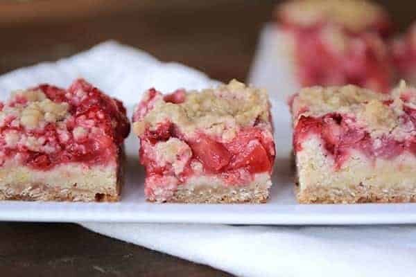 Three strawberry shortcake bars lined up in a row on a white platter.