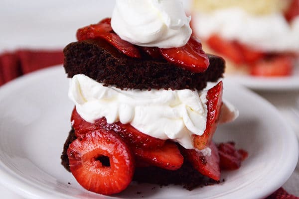 A piece of layered chocolate strawberry shortcake on a white plate.