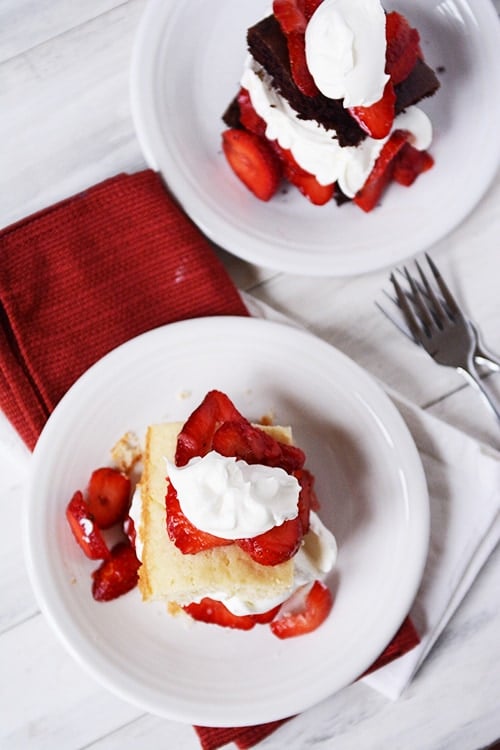 A top view of two white plates with a strawberry shortcake on one and chocolate strawberry shortcake on the other.