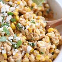 Mexican street corn salad, chopped cilantro, lime with wooden spoon.