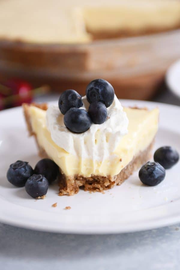 A slice of berries and cream pie on a white plate with a bite taken out.