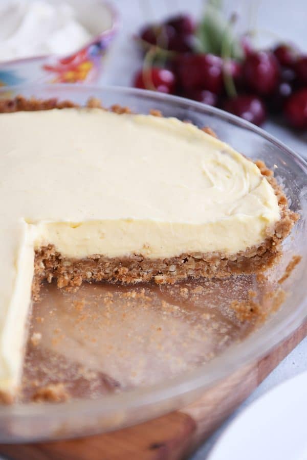 Berries and cream pie in pie plate with a piece taken out.