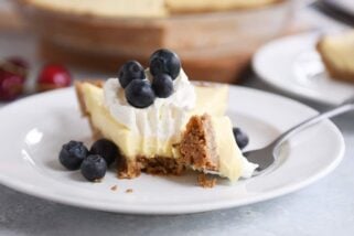 Berries and cream pie on a white plate with a bite taken out.