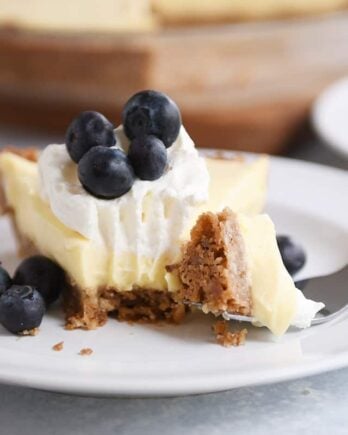 Berries and cream pie on a white plate with a bite taken out.