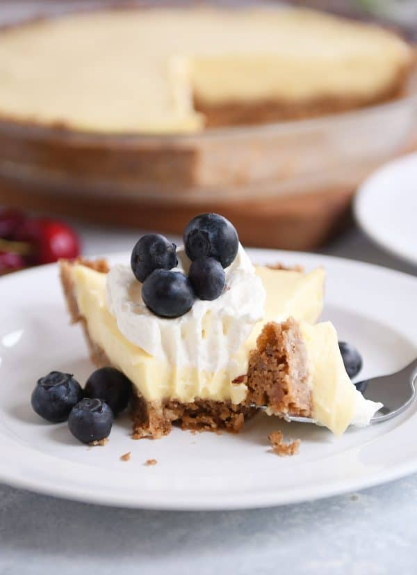 Berries and cream pie on a white plate with a bite taken out.