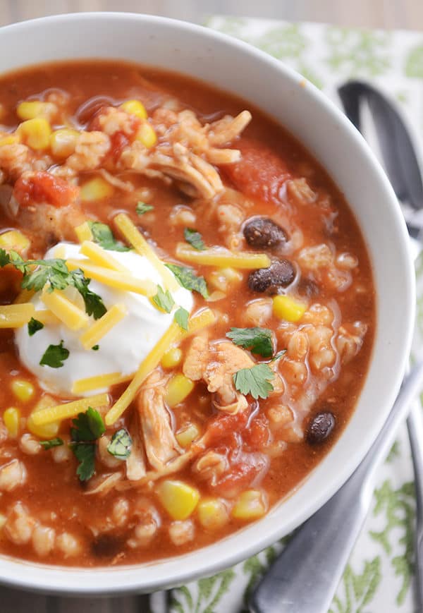 Top view of chicken barley chili topped with sour cream and cheddar cheese.