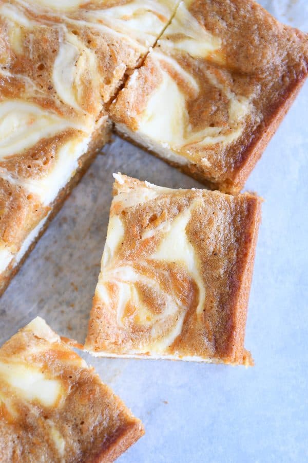 Swirled carrot cake cheesecake bars cut into squares; top down view.