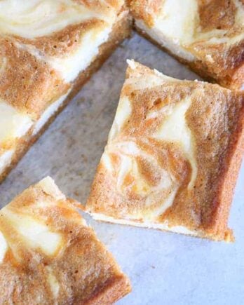 Swirled carrot cake cheesecake bars cut into squares; top down view.