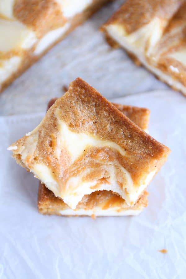 Two carrot cake cheesecake bars stacked on top of each other.