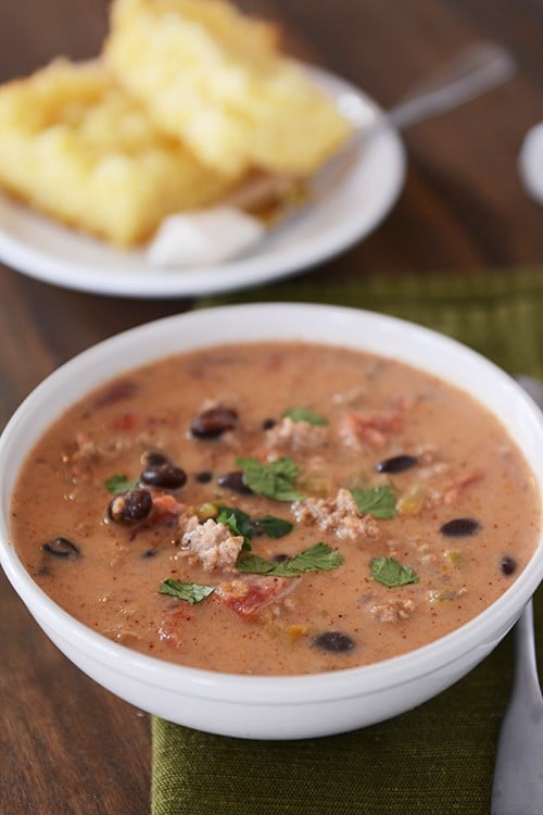 A white bowl of creamy black bean taco soup with cilantro on top.