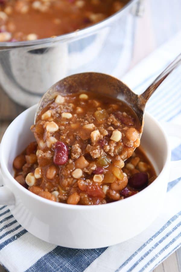 Ladle of taco soup pouring into white bowl.