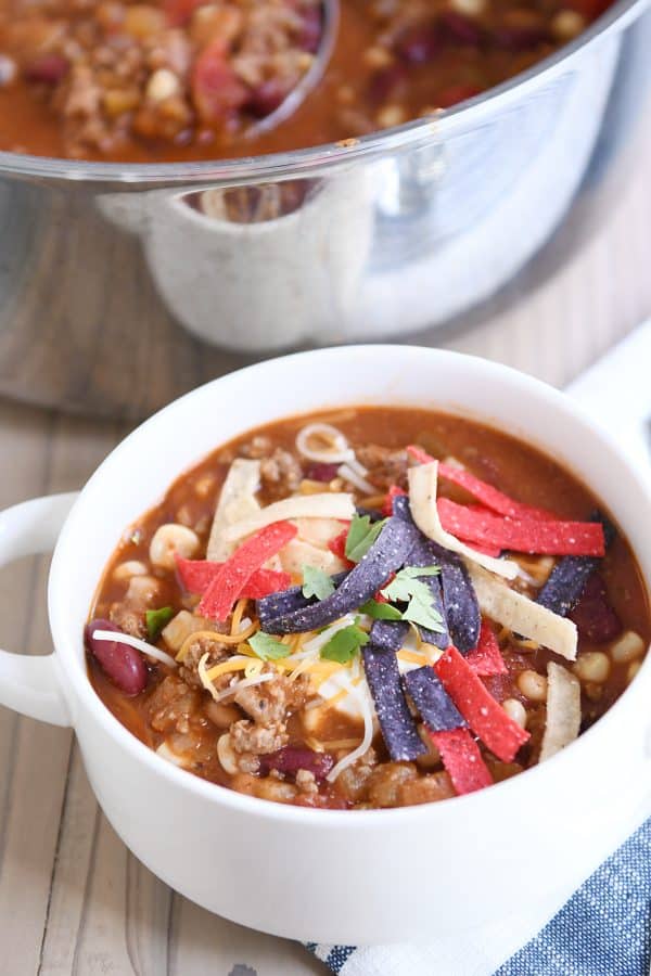 White bowl filled with taco soup, cheese, sour cream and tortilla strips.