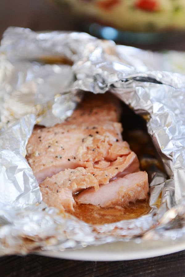 A partially unwrapped tinfoil packet of grilled salmon.