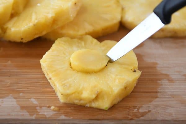 Cutting out the center core of a piece of pineapple.