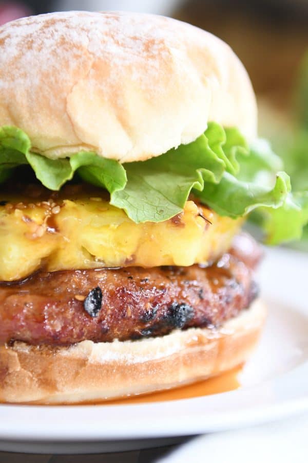 Close up of teriyaki turkey burgers with grilled pineapple, lettuce, and soft bun.
