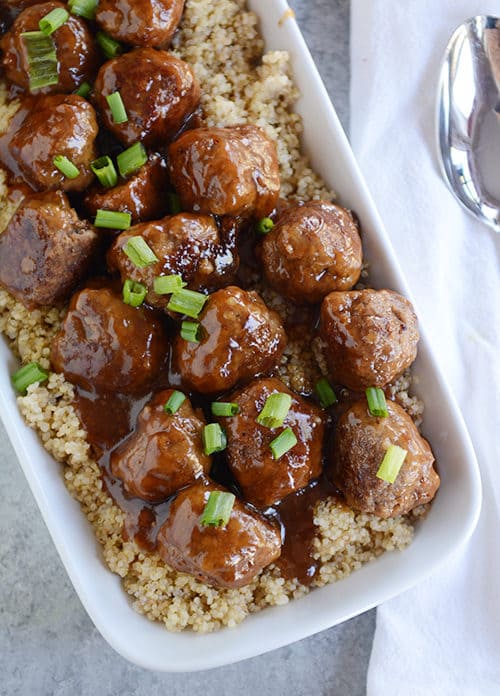 Top view of a white casserole dish full of rice topped with teriyaki coated meatballs.