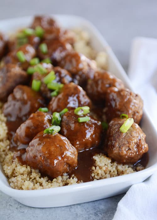 A white casserole dish full of rice and meatballs covered in a teriyaki sauce.
