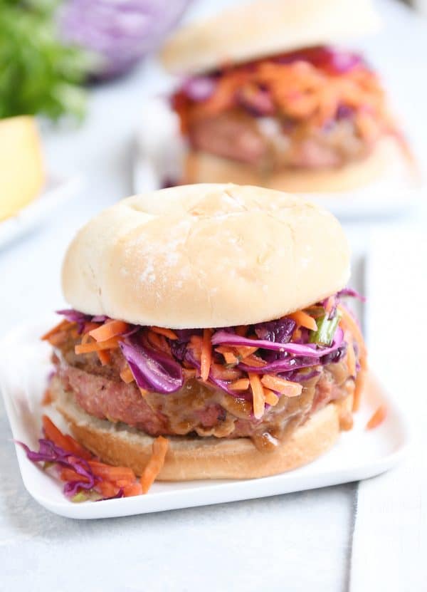 Thai burger with peanut sauce and tangy slow on white square plate.