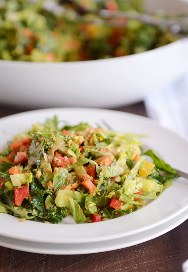 A white plate of chopped Thai salad with the bowl of the rest of the salad behind it.