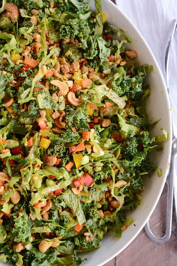 Top view of a large white oval bowl full of chopped Thai salad full of vegetables and cashews.