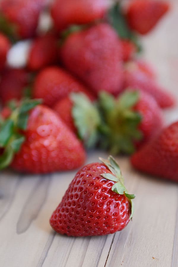 Fresh red ripe strawberries on a wooden countertop.