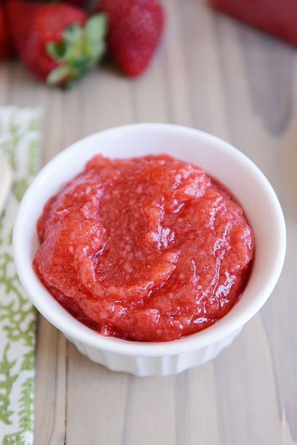 A white ramekin full of fresh strawberry jam.
