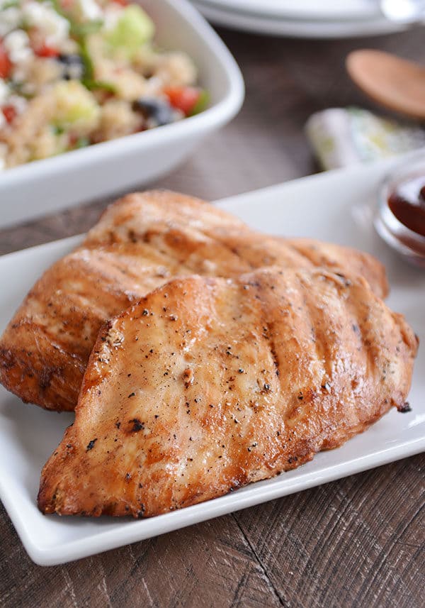 Two grilled chicken breast on a white platter.