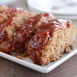 Slices of the best glazed meatloaf on white platter.