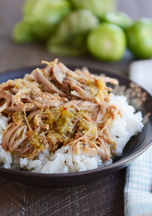 A bowl of cooked white rice topped with shredded pork and tomatillo sauce.