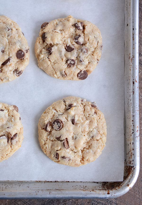 Top view of cooked chocolate chip cookies on a parchment-lined cookie sheet.