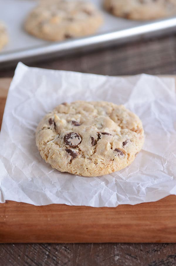 A chocolate chip cookie on a square of parchment paper.