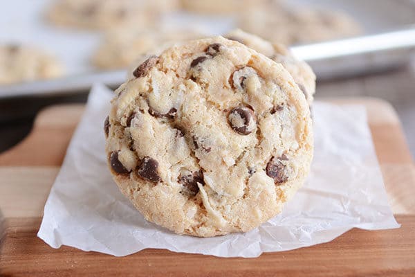 A chocolate chip cookie tipped on it's side on a piece of parchment. 