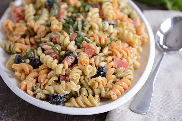 A bowl full of tri-color pasta with olives sprinkled throughout. 