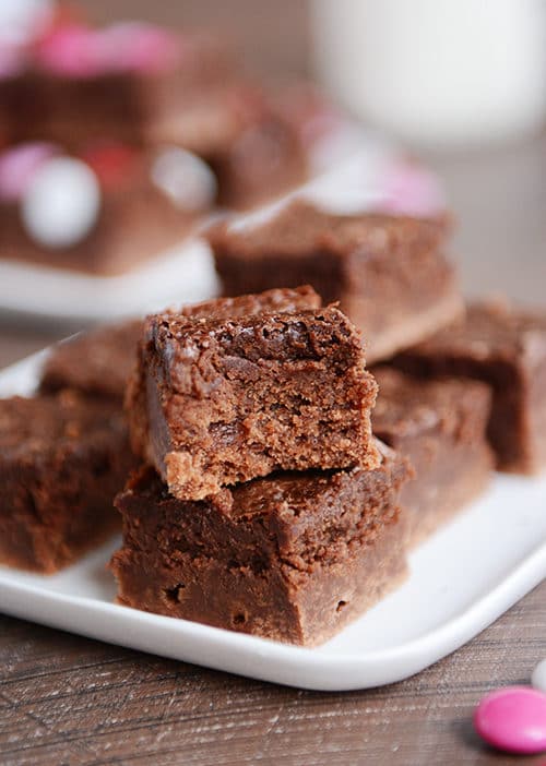 Fudgy truffle brownies cut into squares and stacked on a platter.