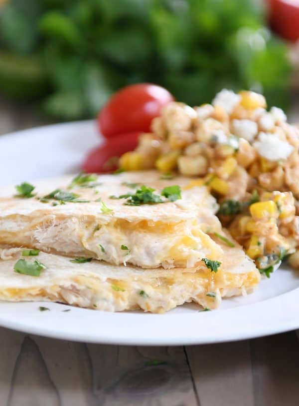 Stack of two triangles of tuna quesadilla melts on white plate with corn salad.