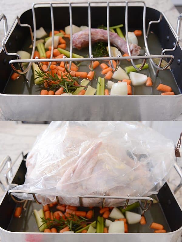 A roasting pan with chopped vegetables and a covered turkey on top.