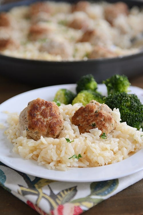 A plate of rice and meatballs with a side of broccoli.