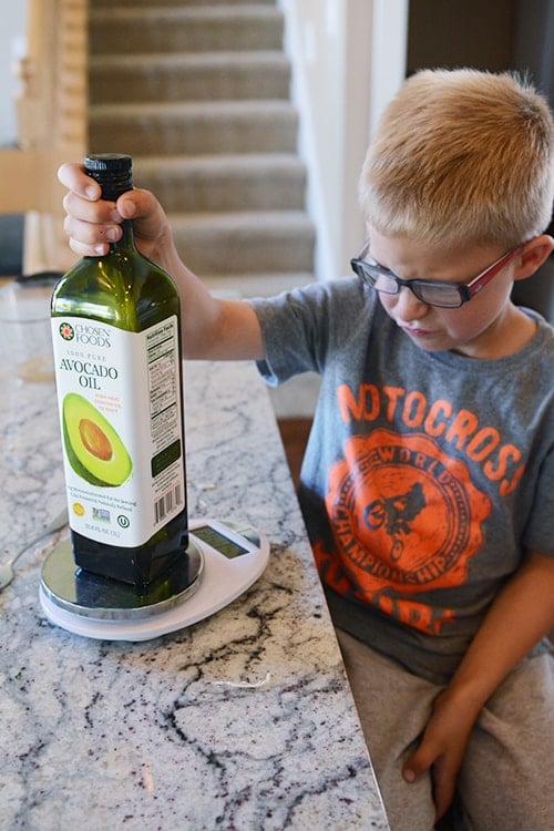 A little boy looking at a jar of avocado oil. 