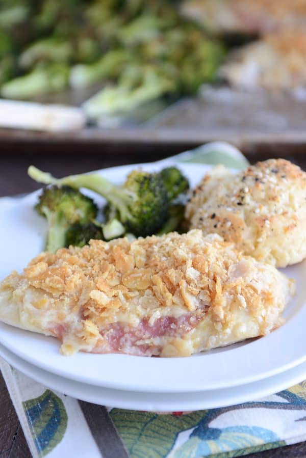 Unstuffed sheet pan chicken cordon bleu on white plate with broccoli and biscuit.