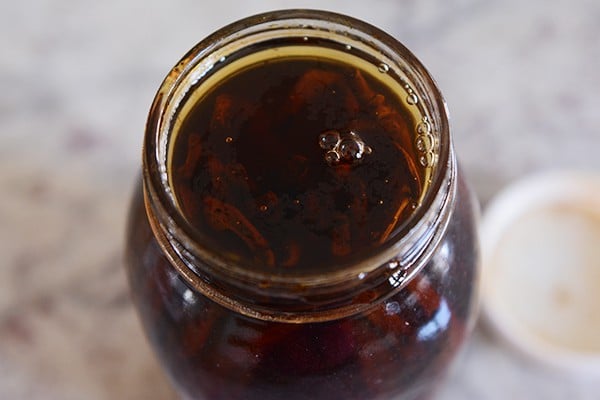 Top view of a mason jar full of alcohol-soaked vanilla beans. 