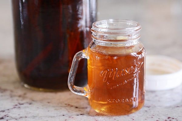 Homemade vanilla extract in a glass mug.