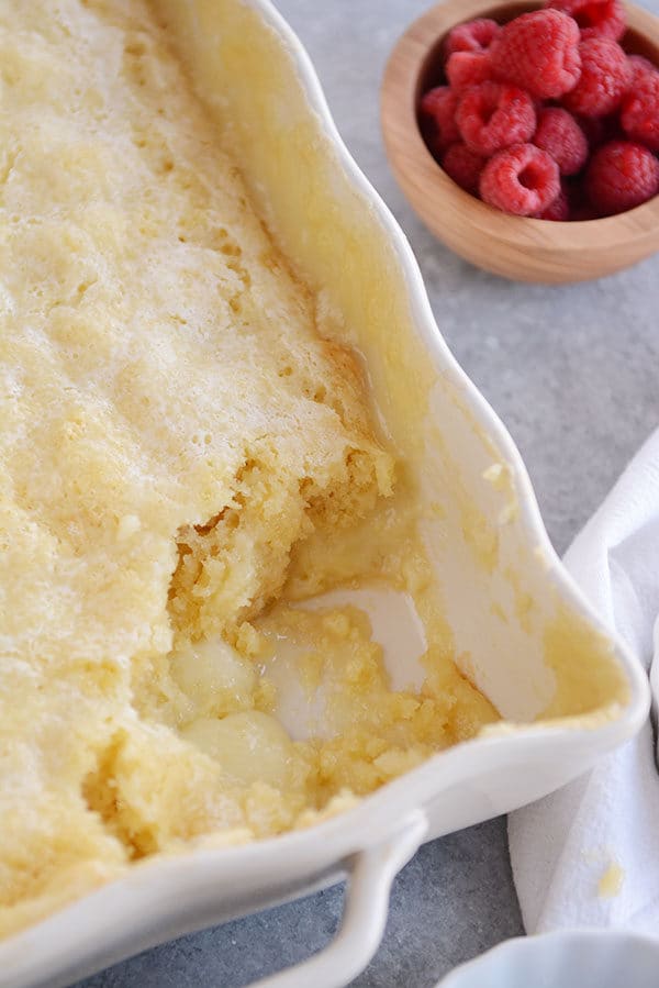 A white dish full of vanilla pudding cake with a scoop taken out of the corner.