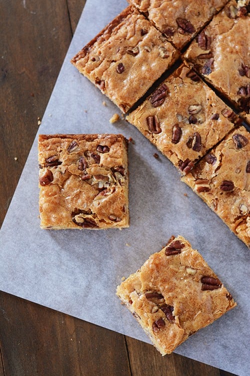 Cut up white chocolate pecan brownies on a piece of parchment paper.