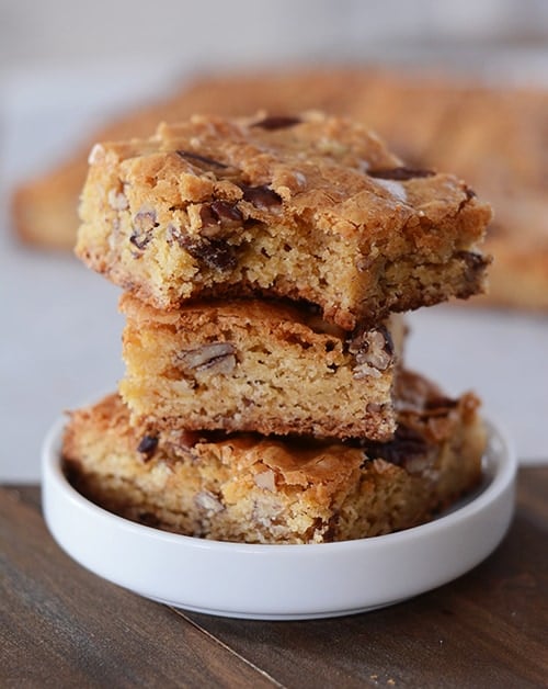 A stack of white chocolate pecan brownies in a white ramekin. 